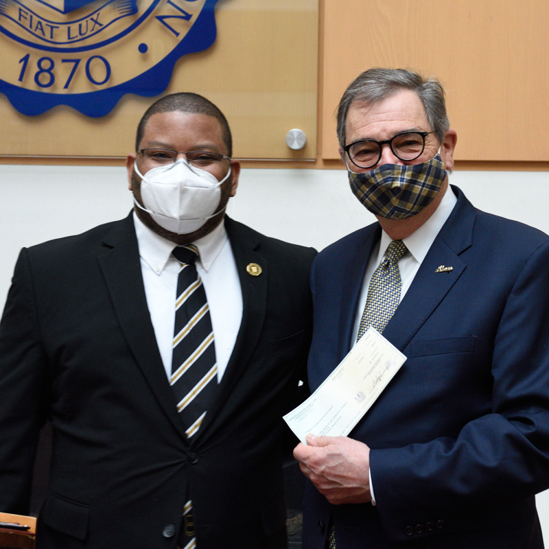 President Miller accepts the donation from Ron Stovall of Alpha Phi Alpha Fraternity.