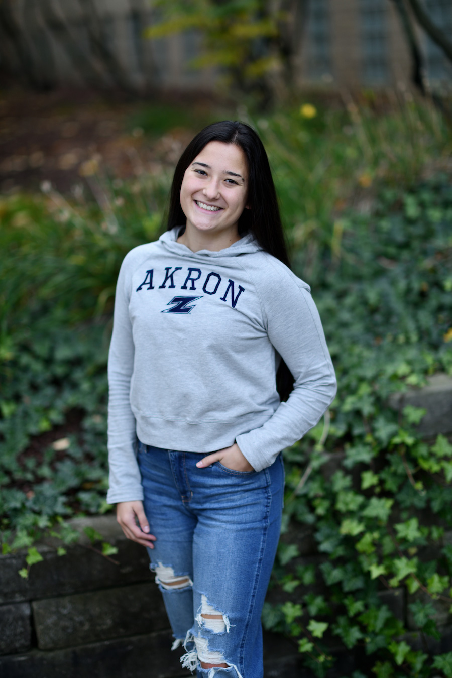 Photo of woman in gray hoodie against green space background.